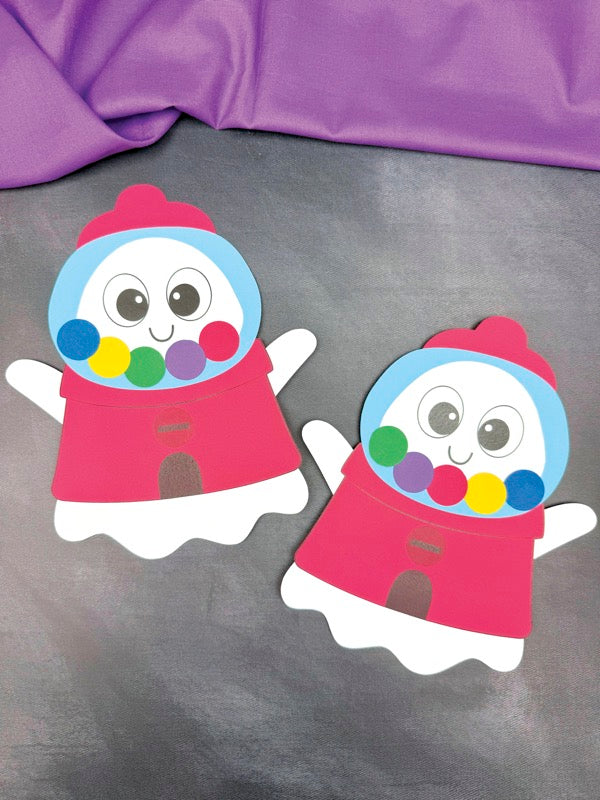 Two colorful paper cutouts of ghosts disguised as a gumball machine on a purple background