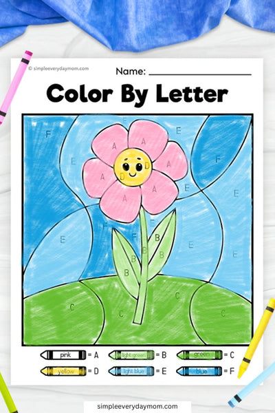 A "Color by Letter" worksheet of a pink flower with a smiling yellow center, green stem, and blue sky, with letters guiding the coloring.