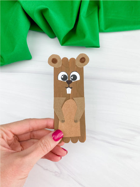 hand holding groundhog popsicle stick craft