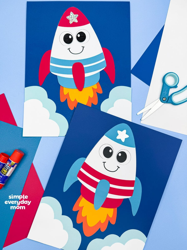 Two patriotic rocket crafts on blue background with scissors, paper, and glue 