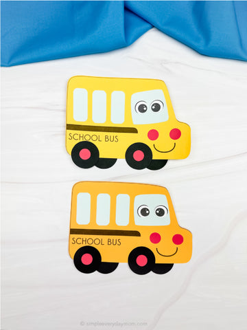 Two yellow school bus crafts on a white background with blue fabric above.