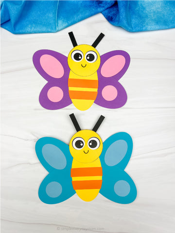 Two colorful butterfly crafts on a white background with blue fabric at the top.
