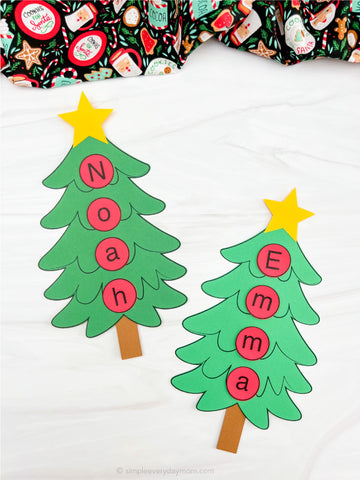 Two paper Christmas trees with letters spelling names on a white background