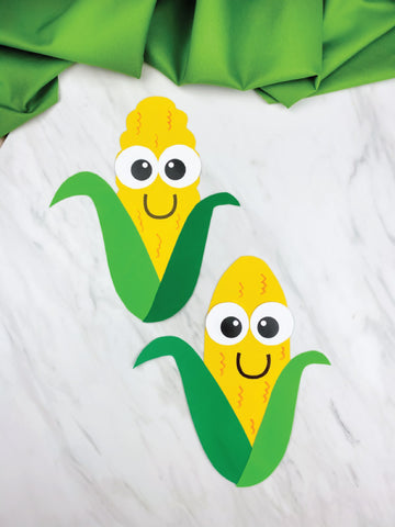 Two cartoon-style corn on the cob crafts with faces on a white background
