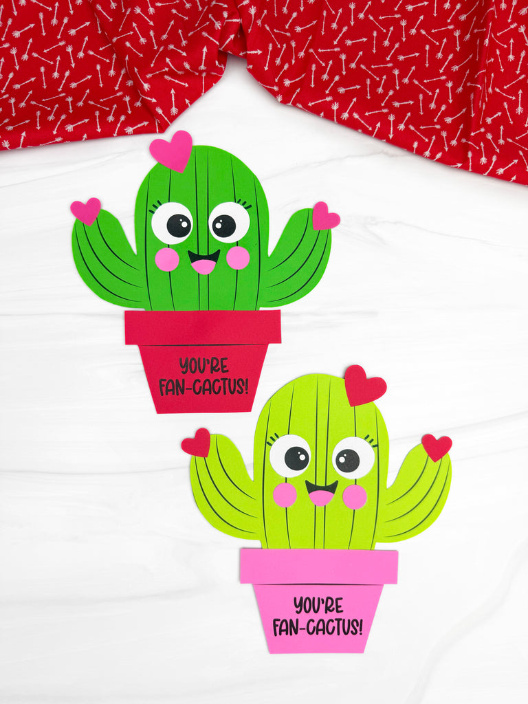 Two cactus Valentine craftst on a white background with red fabric on top. 