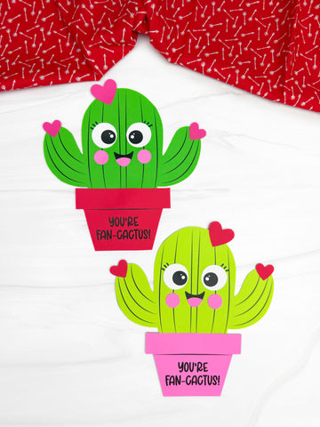 Two cactus Valentine craftst on a white background with red fabric on top. 