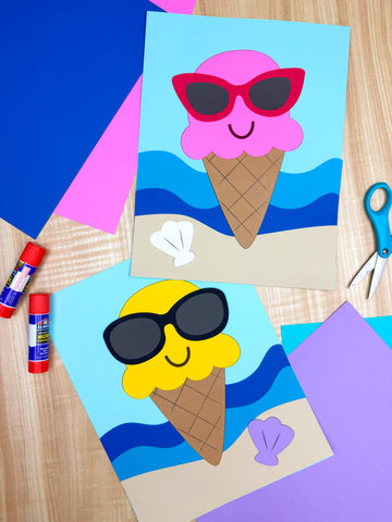 Two paper craft ice cream cones, one with pink and one with yellow scoops, each wearing oversized sunglasses and smiling, set against a beach background with waves and paper seashells. Art supplies like glue sticks, scissors, and colorful paper are arranged around them on a wooden surface.
