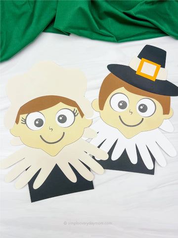 Handmade pilgrim figures made from paper with a green fabric background