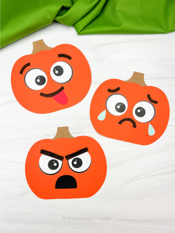 Three paper pumpkin crafts with different facial expressions on a white background.