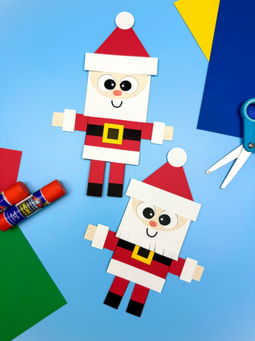 Two Santa shape crafts on blue background with paper, scissors, and glue