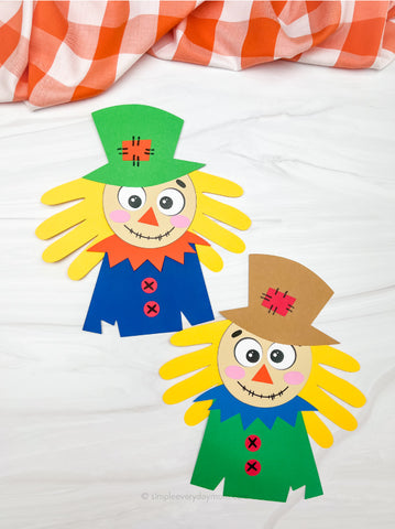 Two colorful scarecrow crafts made from handprints on a white background with a checkered cloth.