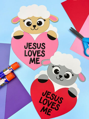 Two faith based sheep crafts on blue background with paper, scissors & glue
