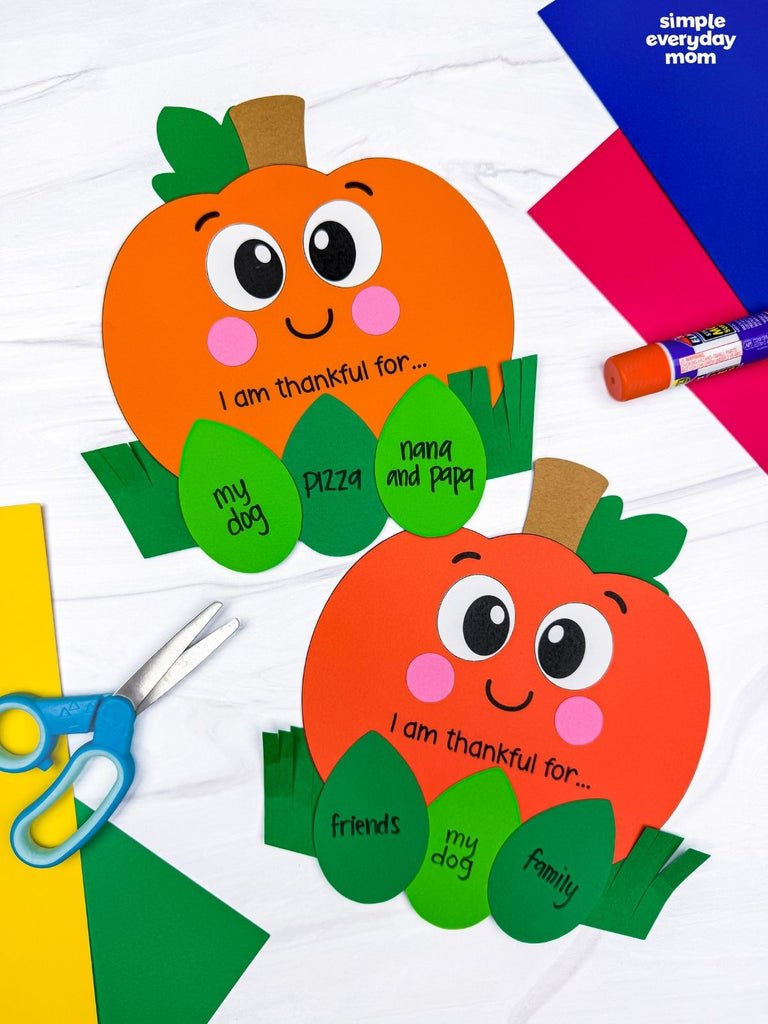 Two thankful pumpkin crafts on white background with paper, scissors, and glue. 