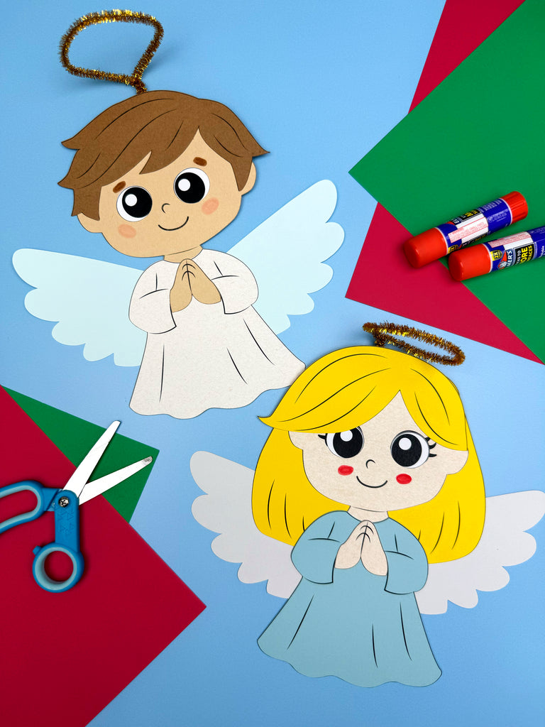 Two paper angel crafts with brown hair and blonde hair on a colorful background with markers and scissors.