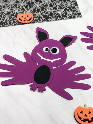 Purple bat craft made from paper with Halloween decorations on a white background