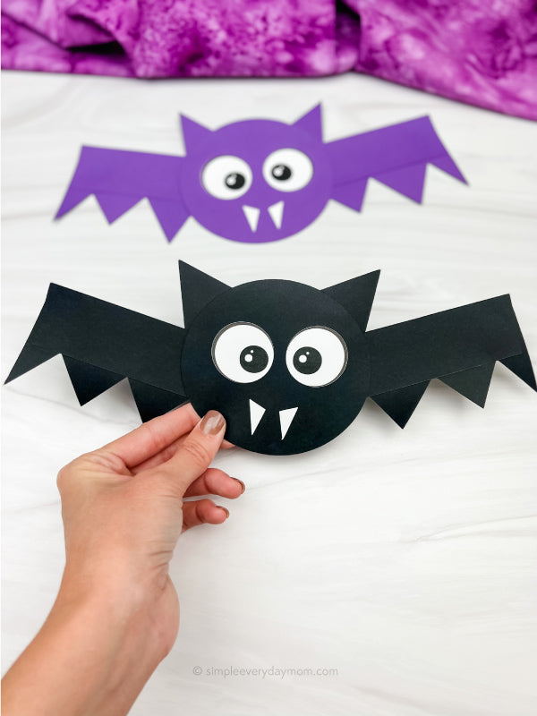 hand holding bat shape craft with a 2nd bat in the background.