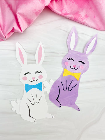 Two cartoon-style bunny crafts, one white with a blue bow tie and one purple with a yellow bow tie, on a light background.