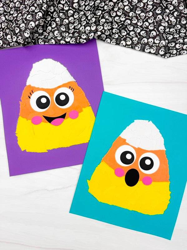 Two colorful craft cards featuring a cute paper-candy corn character on purple and blue backgrounds, styled on a white surface with a black and white skull-patterned fabric at the top.
