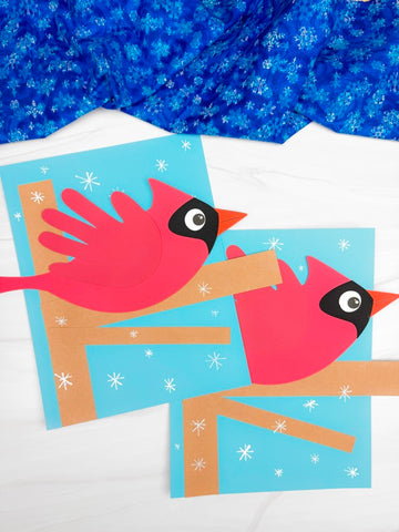 Two handprint cardinal crafts on white background with blue snowflake fabric