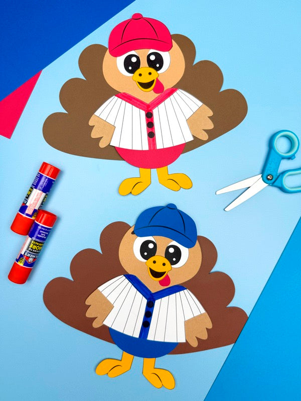 Two turkey crafts disguised as baseball players on a blue background with glue and scissors.