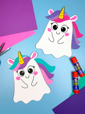Two paper unicorn ghosts disguise crafts on a blue background with craft supplies.