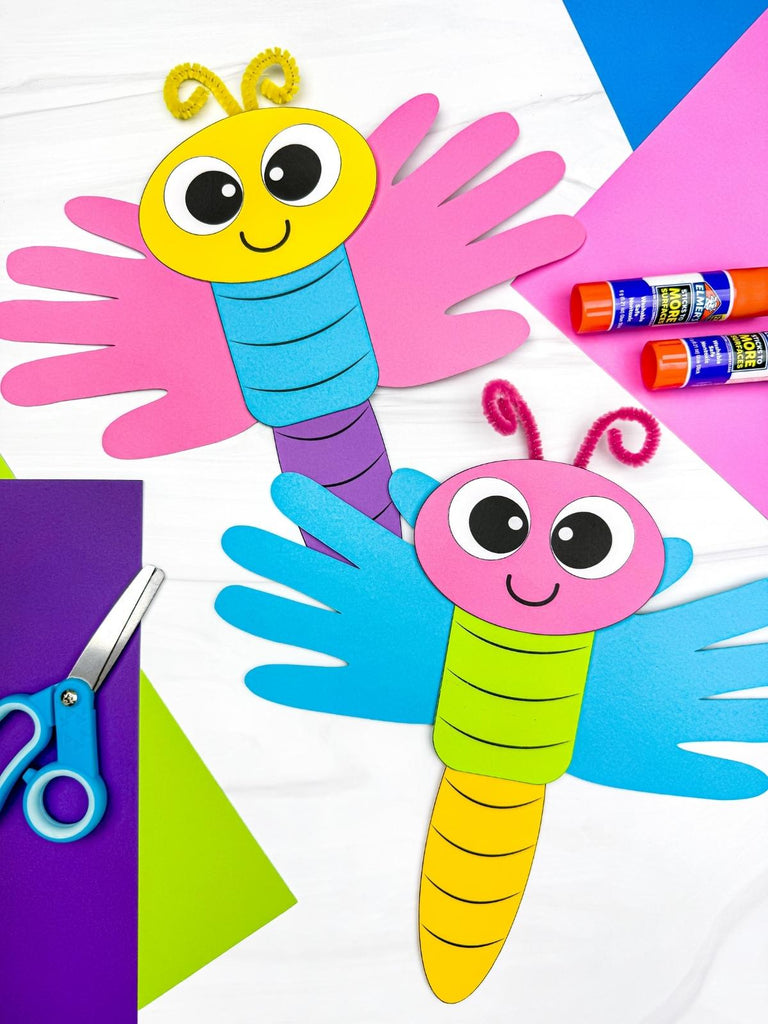 Colorful handprint dragonflies on a white background with craft materials.