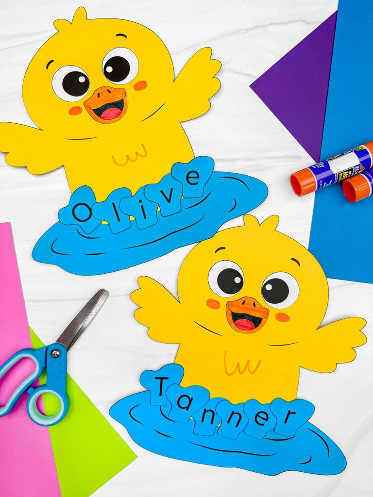 Two yellow duck name crafts, surrounded by craft supplies, on a colorful background.
