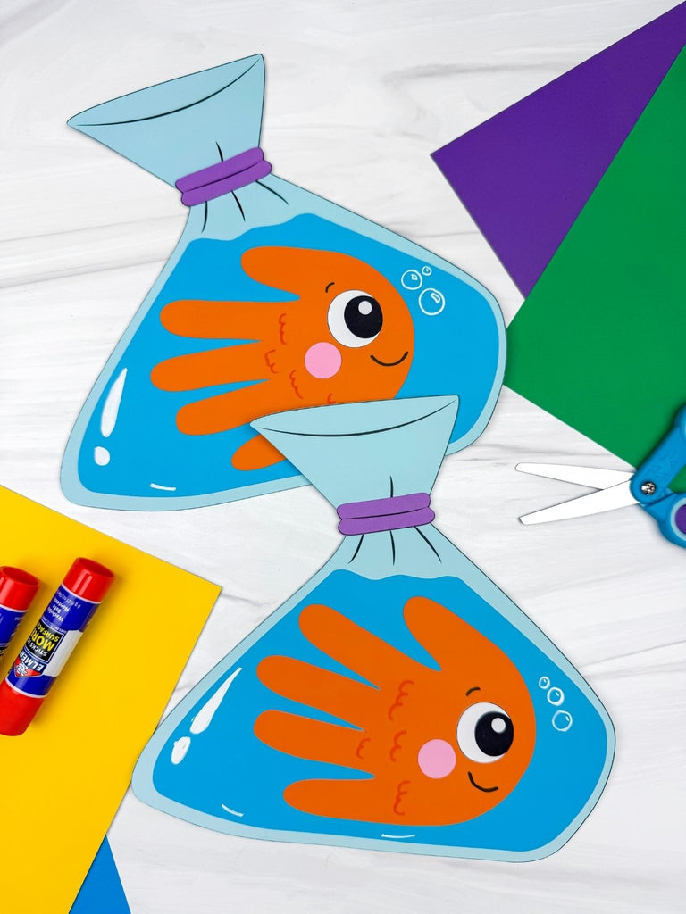Handprint fish in a fishbowl craft with glue sticks on a white background