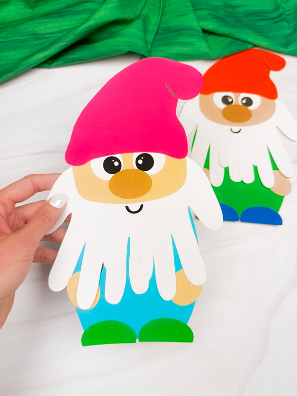 hand holding handprint gnome craft with a 2nd gnome in the background