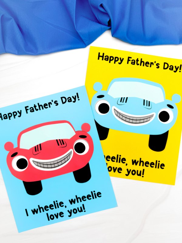 Two car Father's Day crafts on a white background with blue fabric on top 