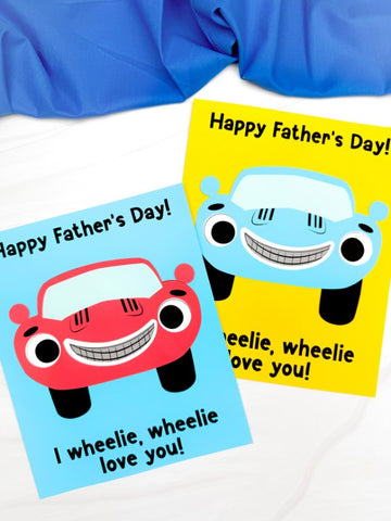 Two car Father's Day crafts on a white background with blue fabric on top 