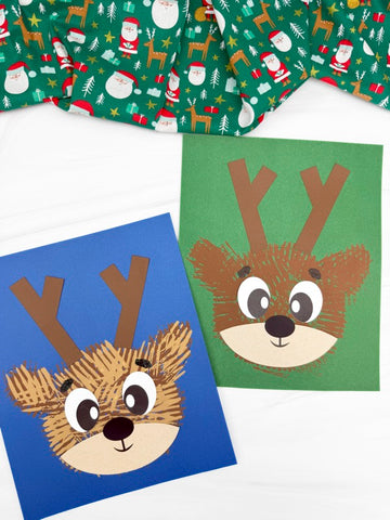 Two fork painted reindeer crafts on white background with Christmas fabric