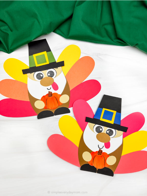 Two colorful paper gnome turkey crafts crafts with pilgrim hats on a white background.