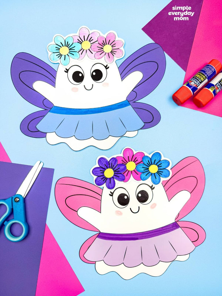 Two cute paper fairy ghost crafts on a light blue background with craft supplies including scissors, glue sticks, and colored paper.  