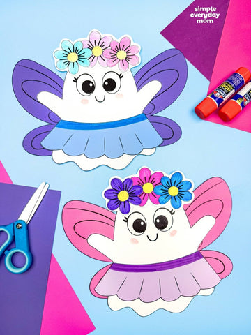 Two cute paper fairy ghost crafts on a light blue background with craft supplies including scissors, glue sticks, and colored paper.  