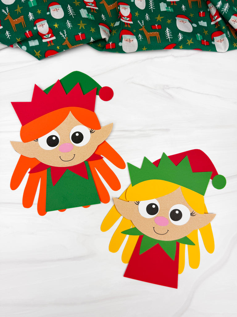 2 handprint girl elf crafts on marble background with fabric on top
