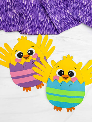 Two handprint Easter chick crafts on white background with purple fabric on top