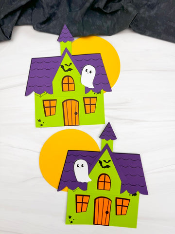 Two Halloween-themed paper haunted houses with ghosts and bats on a white background.