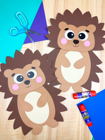 Two paper bag hedgehogs with craft supplies on a wooden surface