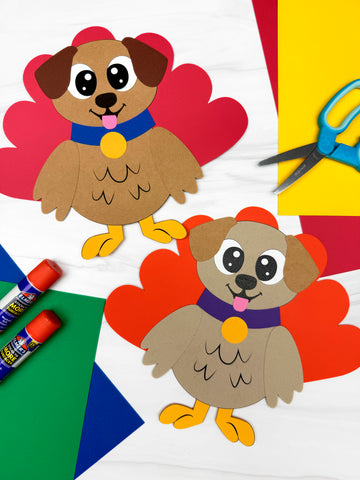 Two paper dog turkey disguise crafts with colorful paper and scissors on a white background