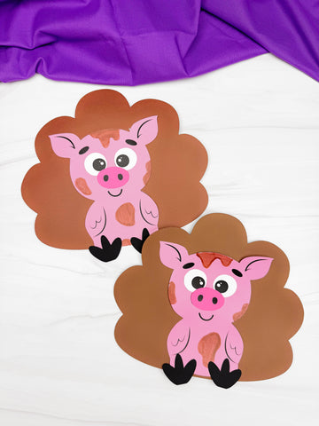 Two turkey disguised as pigs crafts on a white background with purple fabric. 