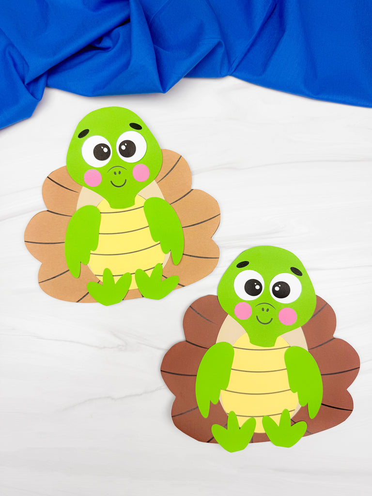 Two turtle turkey disguise crafts on white background with blue fabric on top