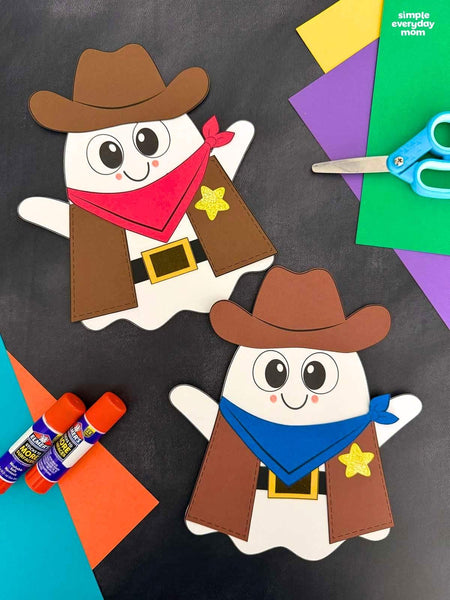 Two cowboy ghost craft cutouts displayed on a dark background with colorful craft supplies including paper, scissors, glue, and markers.
