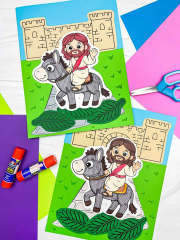 Colorful paper craft activity with Jesus and donkey on a green background, surrounded by craft supplies.