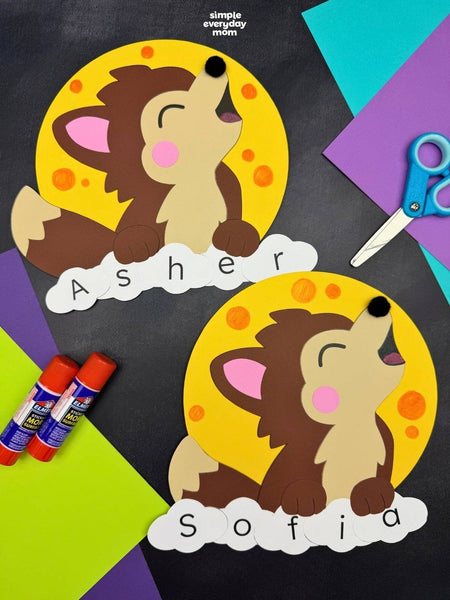 Two personalized craft werewolf cutouts on a dark gray background with colorful paper, scissors, and glue sticks. The top cutout says 'Asher' and the bottom says 'Sofia'.