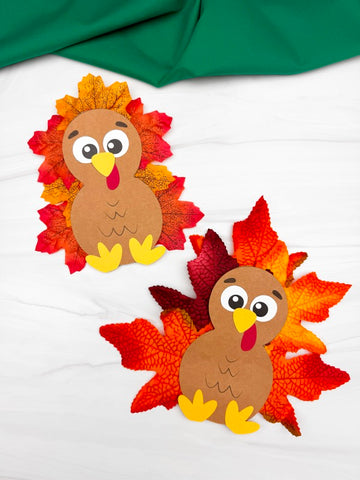 Two turkeys with leaf feathers on a white background with green fabric above.