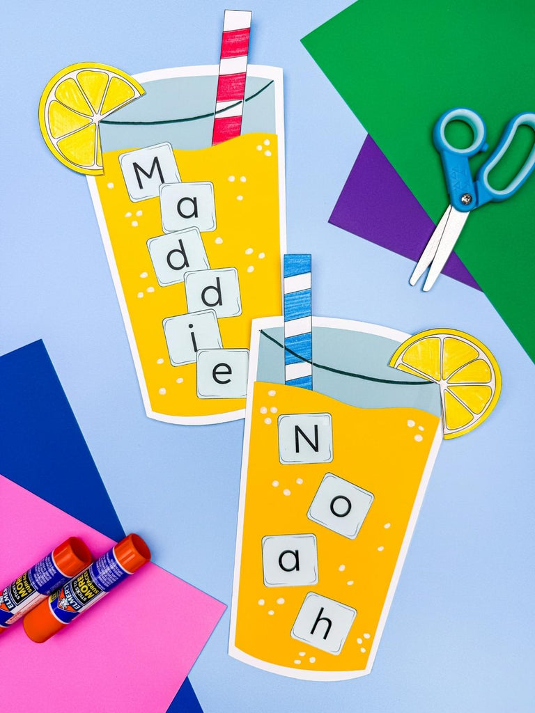 2 lemonade name crafts on blue background with colored paper, scissors, and glue sticks 
