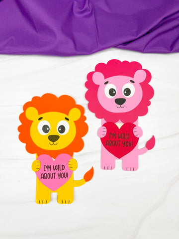 Two lions Valentine crafts holding hearts with text on a white background