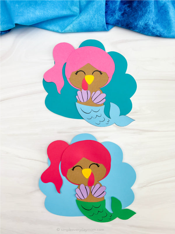 Two mermaid turkey disguise craft on white background with blue fabric
