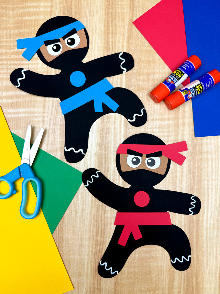 Two gingerbread ninjas with colored markers and scissors on a wooden surface